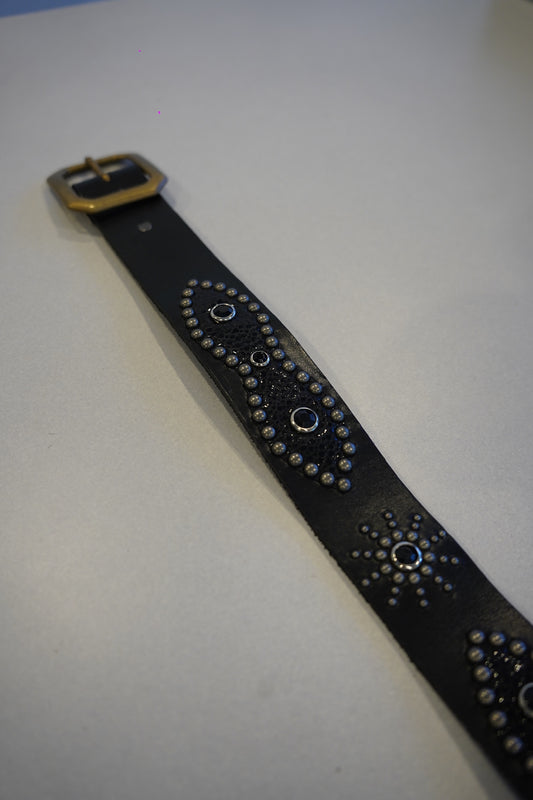 Vintage black studded leather belt coiled view showing pyramid stud pattern and aged leather finish