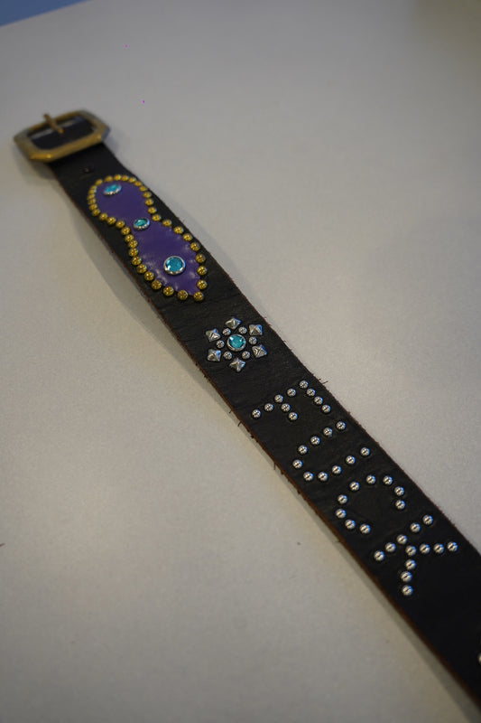 Vintage studded black belt laid flat with purple painted panel, turquoise gem star and stud-spelled text