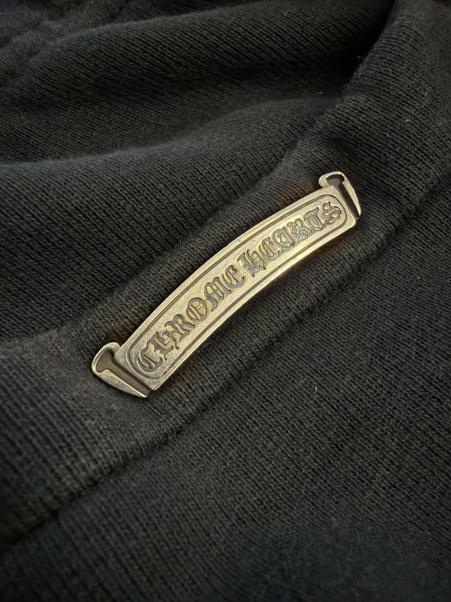 Chrome Hearts Paper Jam sweatpants close-up of metallic gothic scroll brand label on black fabric