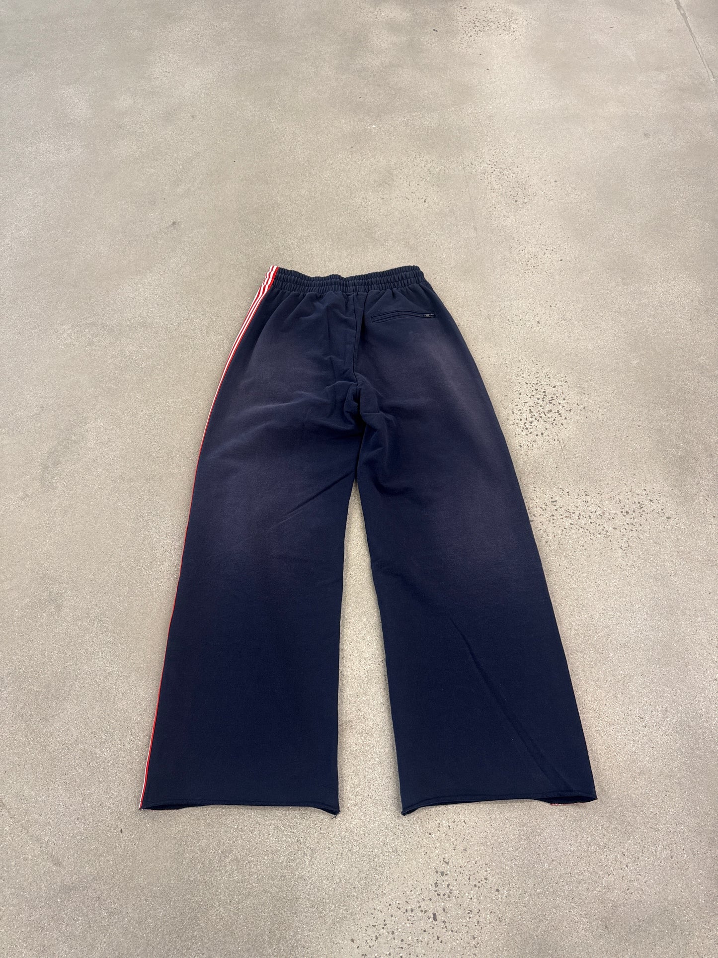 Rear view of Happy Memories Don't Die navy track pants showing red striping and wide straight-leg silhouette
