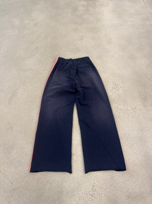 Rear view of Happy Memories Don't Die navy track pants showing red striping and wide straight-leg silhouette