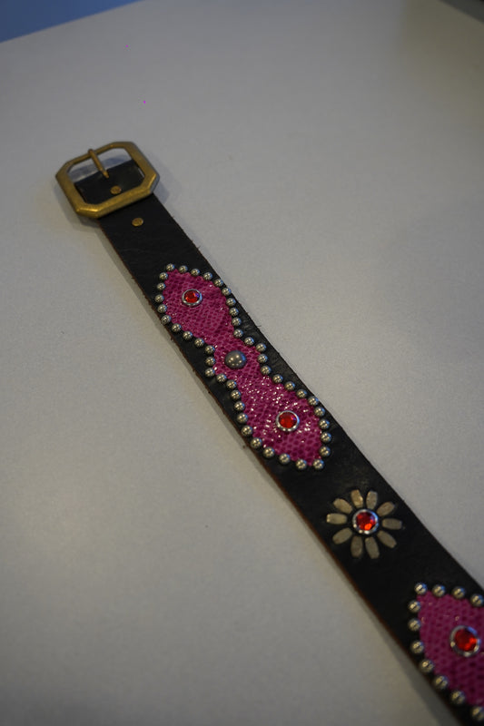 Flat view of vintage black leather belt with pink snakeskin studded medallions and brass buckle detail.