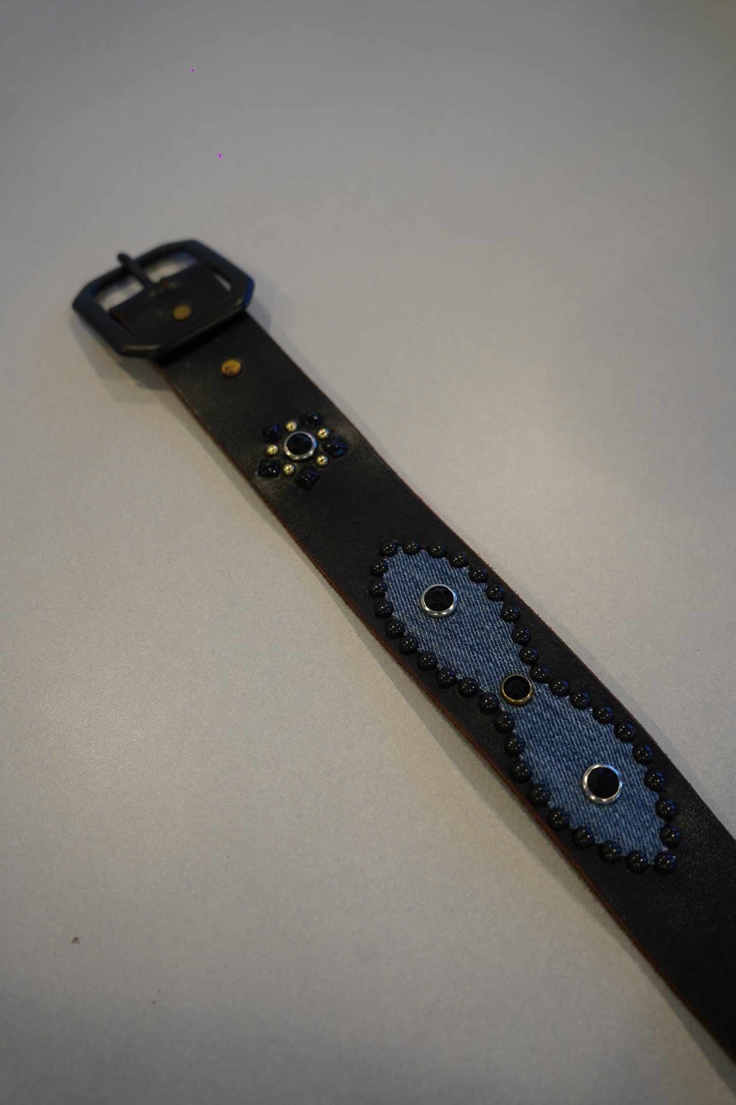 Vintage studded black leather belt detail showing pyramid stud pattern and worn vintage finish.
