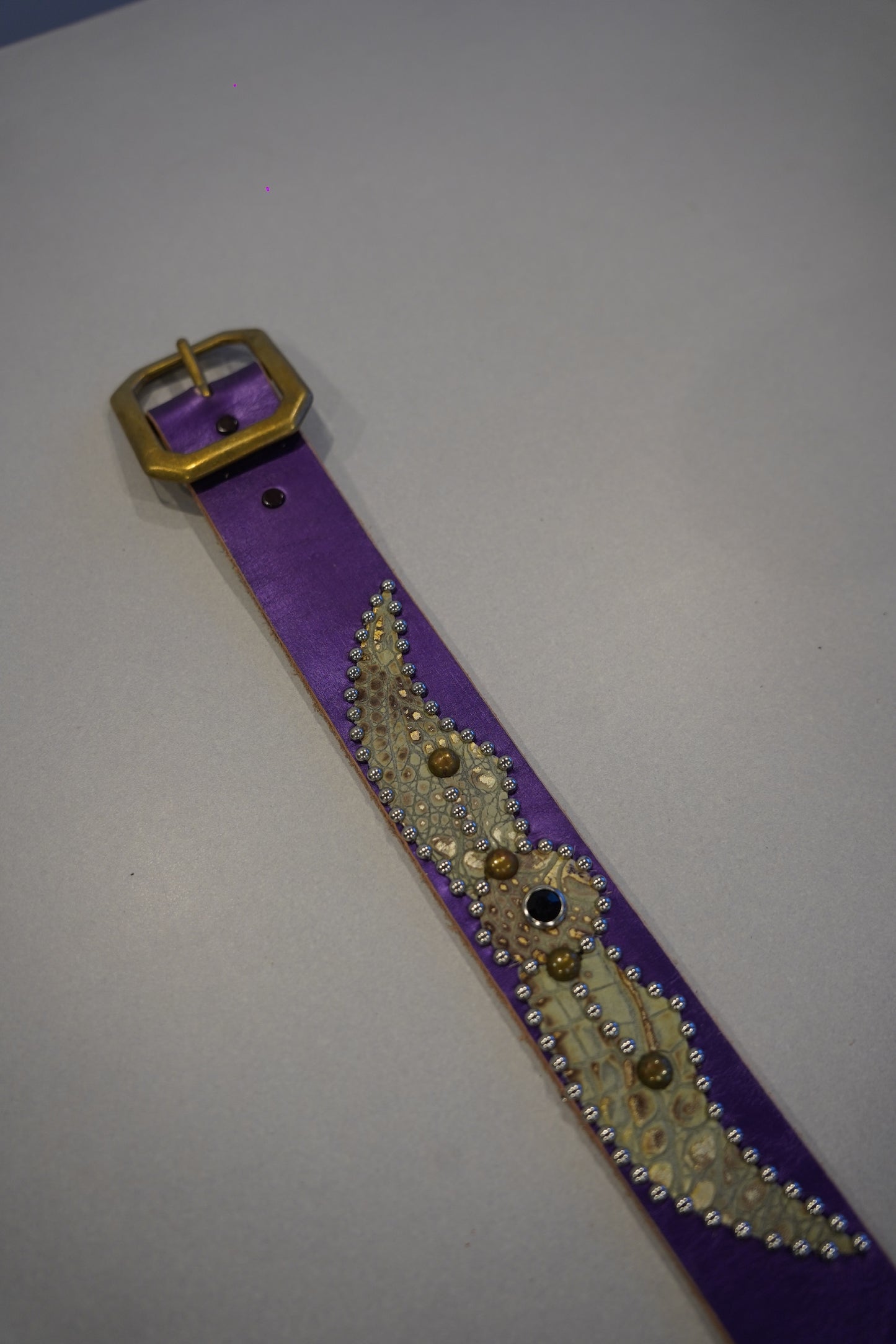 Vintage purple studded belt laid flat showing brass buckle, snakeskin wing detail and beaded silver edging
