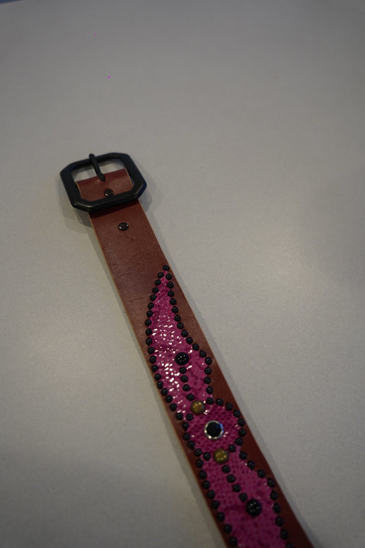 Vintage winged studded leather belt detail showing pink snakeskin texture and metal stud accents.