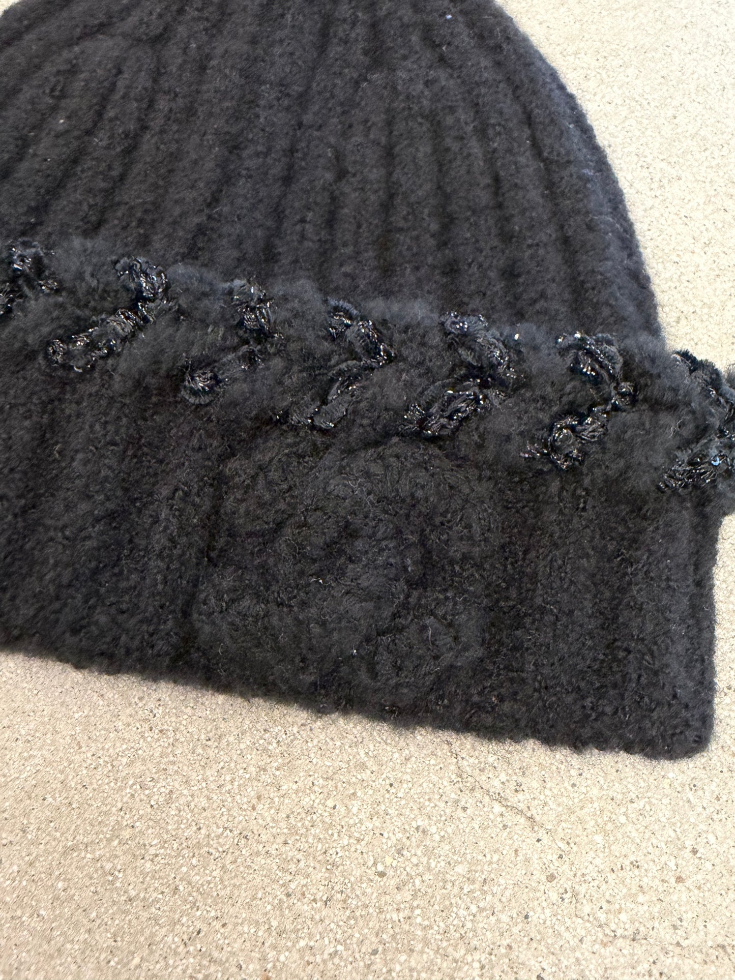Chanel black beanie folded flat showing soft ribbed cashmere knit and embossed CC logo embellishment.