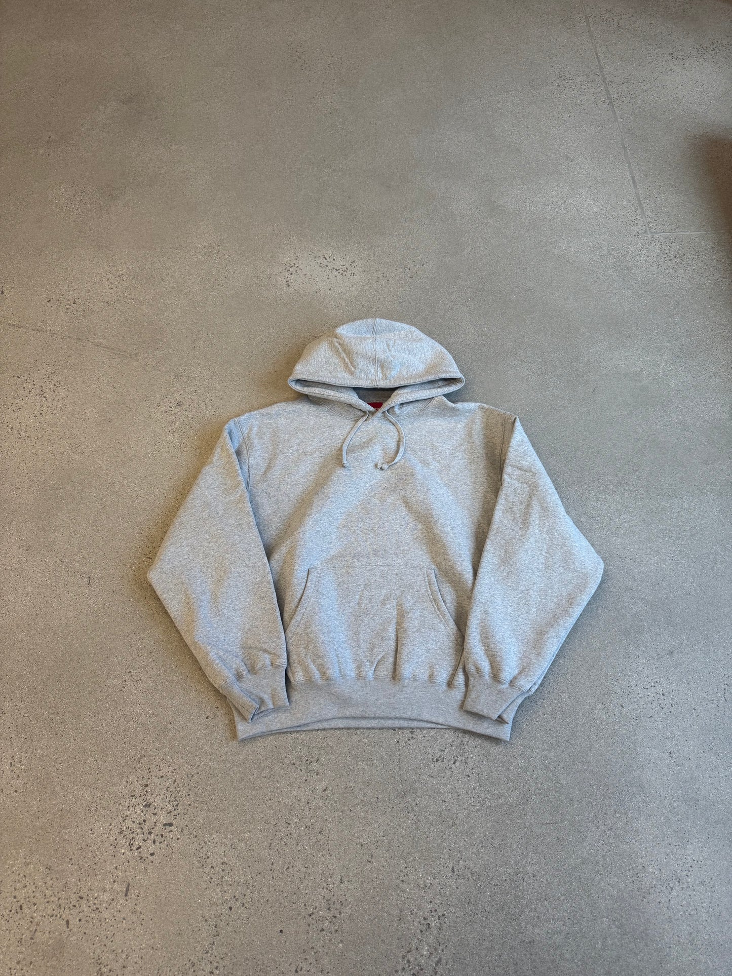 Supreme heather gray pullover hoodie front view with kangaroo pocket and red box logo tag at neck