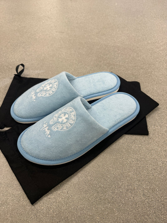 Pair of Chrome Hearts St Barths blue plush slippers displayed on black drawstring dust bag, top view