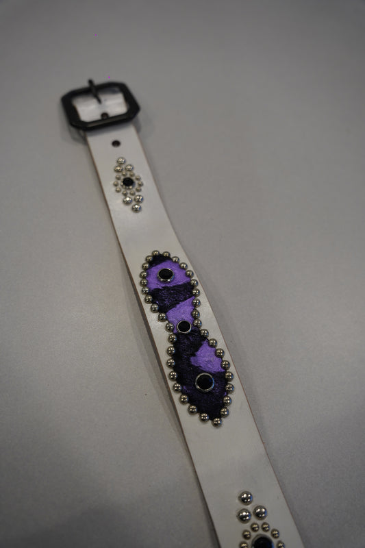 Studded leather belt detail showing purple pony hair inset, silver studs and antique brass buckle hardware.