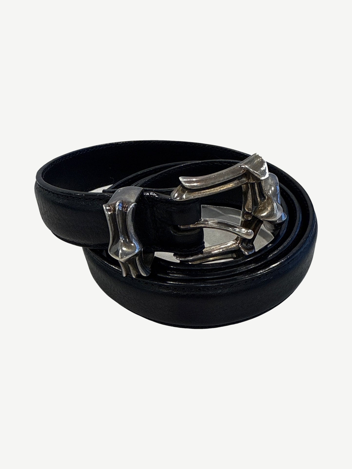 Chrome Hearts three piece black leather belt coiled showing silver dagger buckle and matching tip hardware.