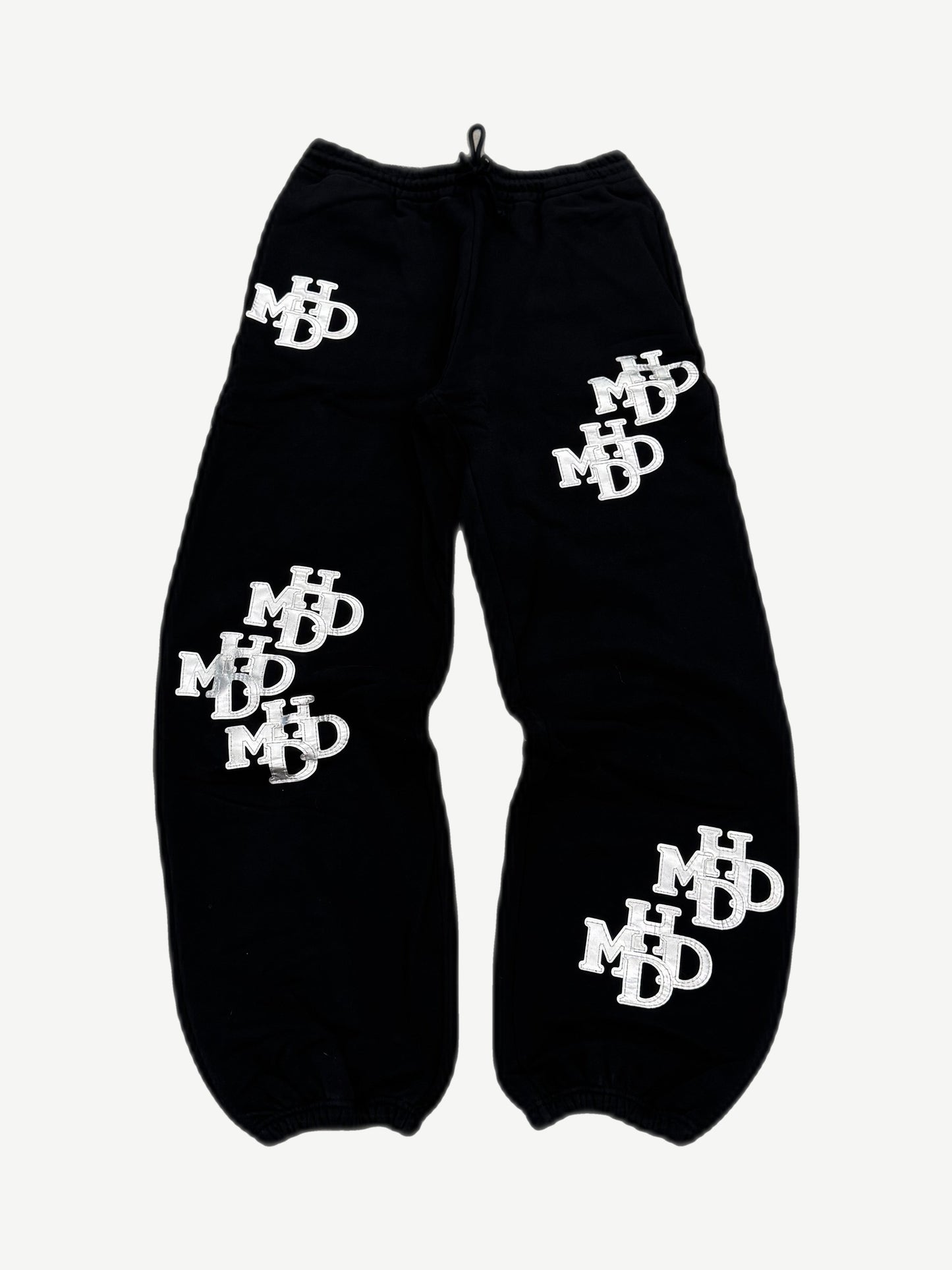 HMDD black sweatpants with all-over silver monogram patches, Happy Memories Don't Die joggers