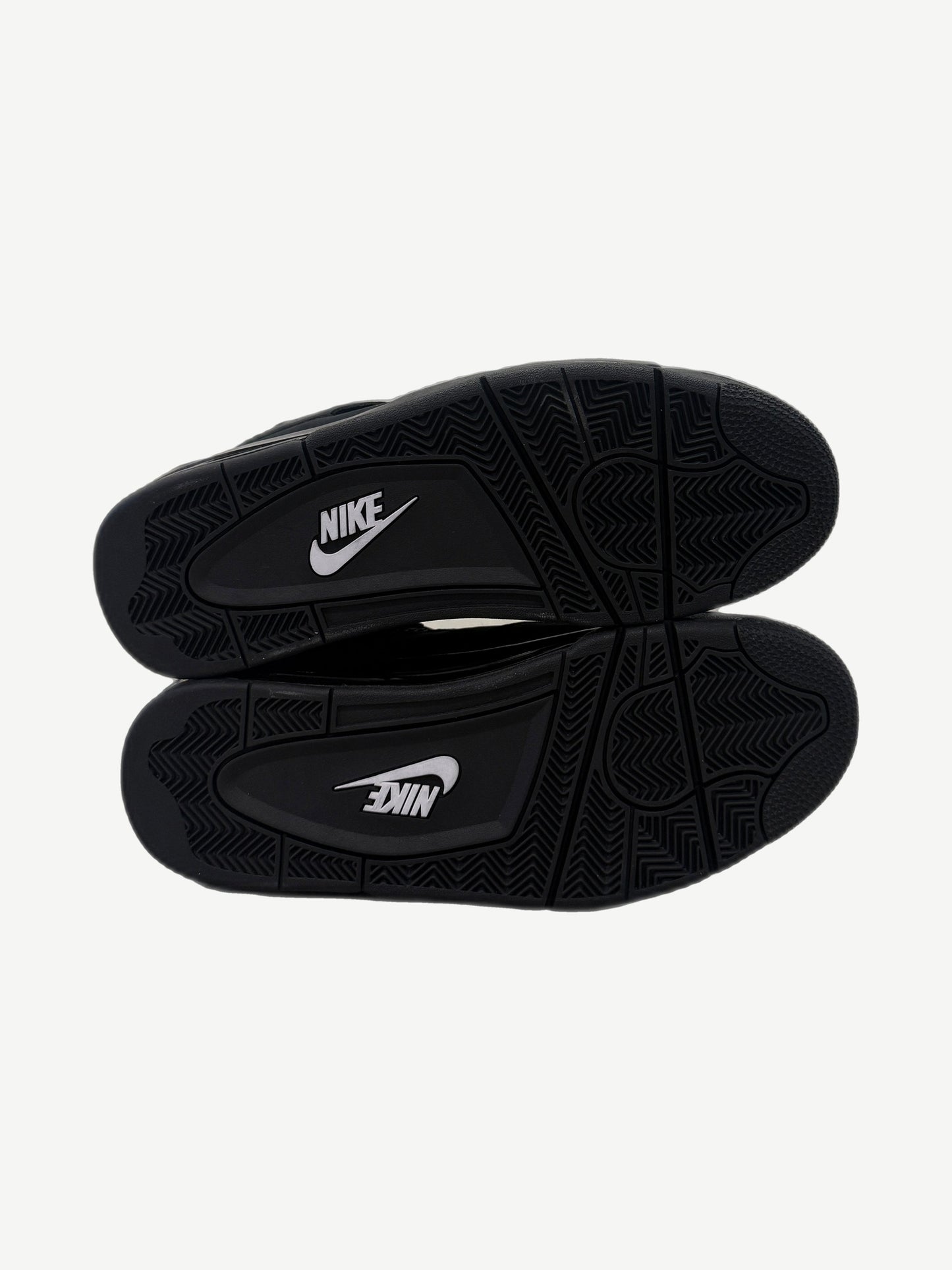Outsole view of Air Jordan 4 Black Cat 2025 with black rubber tread and white Nike branding on midfoot pivot