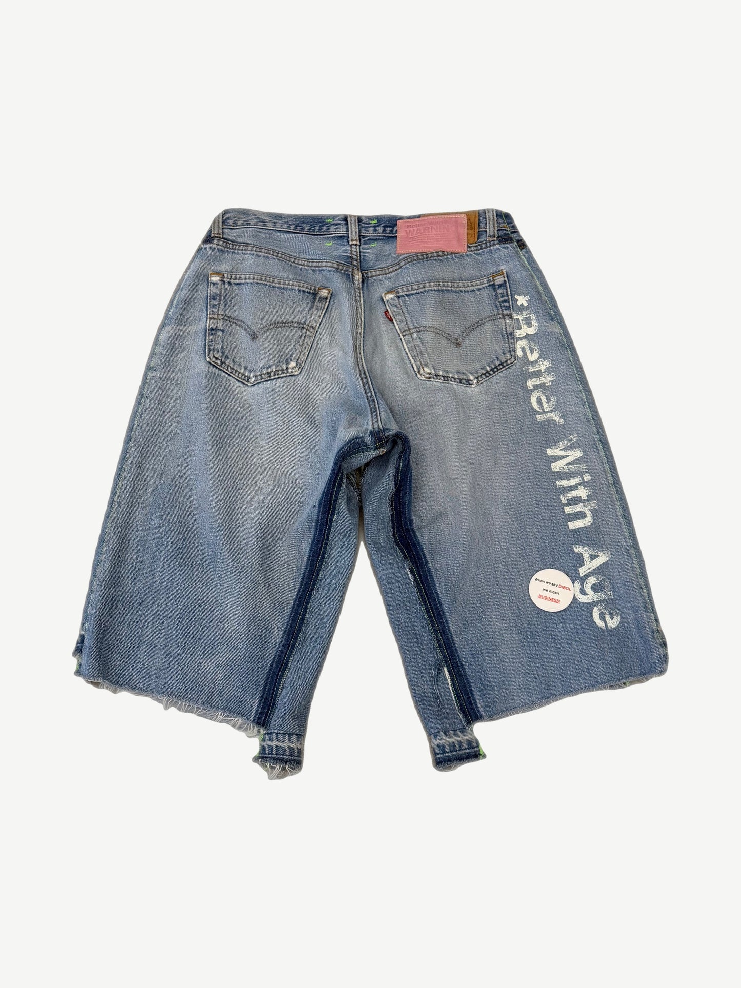 Better With Age pin jean shorts angled view, washed blue denim adorned with custom pin clusters