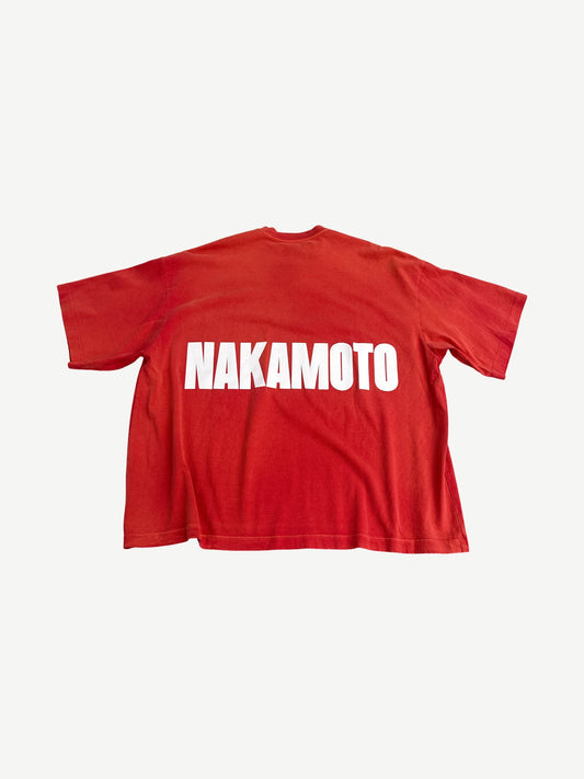 Back of Satoshi Nakamoto red boxy tee with large white Nakamoto block letter print across the shoulders