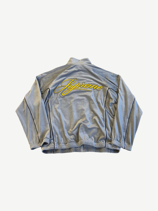 Supreme grey velour track jacket back view with yellow embroidered Supreme script across panel.