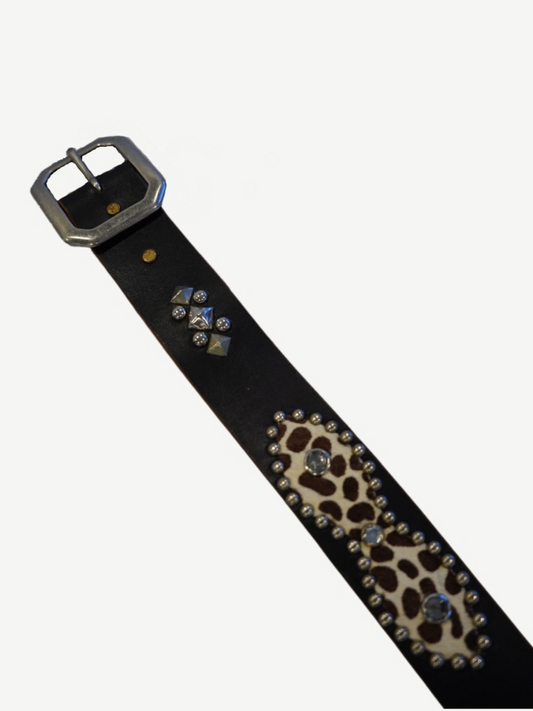 Vintage studded leather belt detail showing chrome buckle, pyramid studs and leopard cowhide patches.