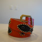 Vintage orange and black leather studded belt with silver pyramid studs and dual-grommet buckle, full length