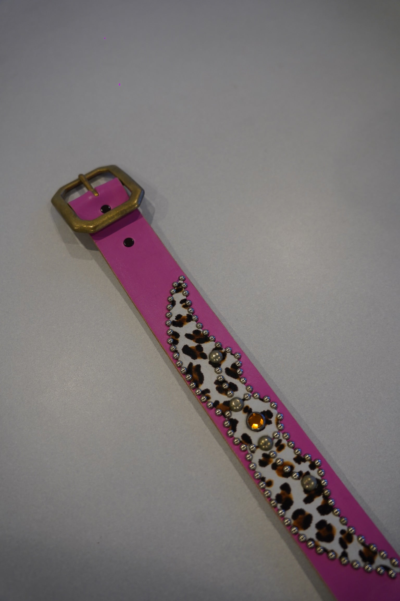 Vintage pink studded leather belt buckle detail, silver pyramid studs on animal print strap