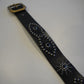 Vintage black studded leather belt coiled view showing pyramid stud pattern and aged leather finish