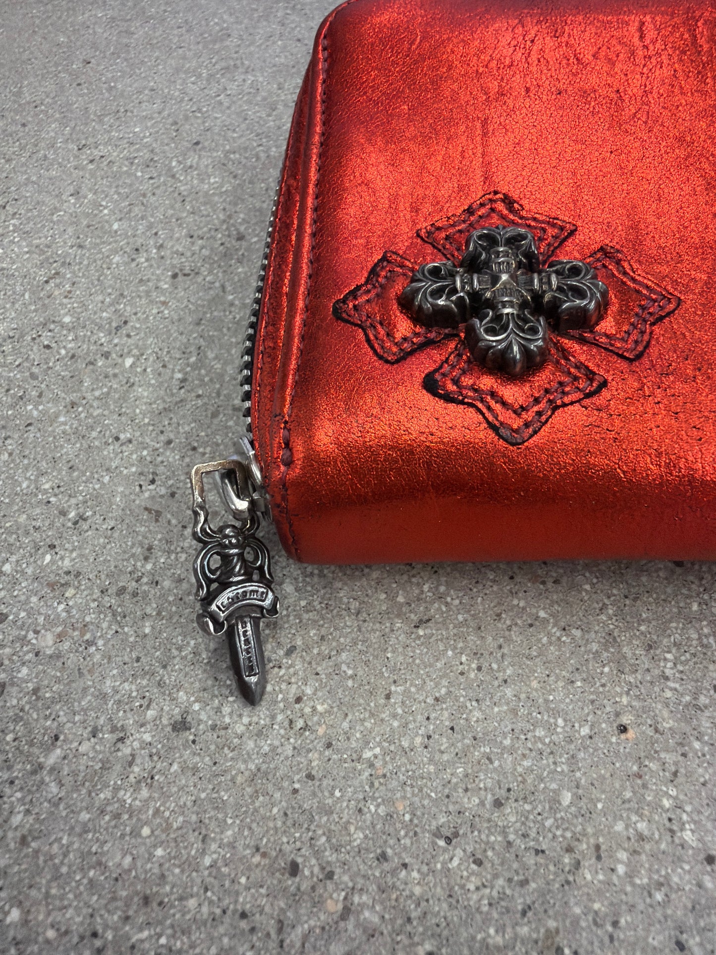 Chrome Hearts red wallet close-up of dagger zipper pull and black plus cross patch on red metallic leather