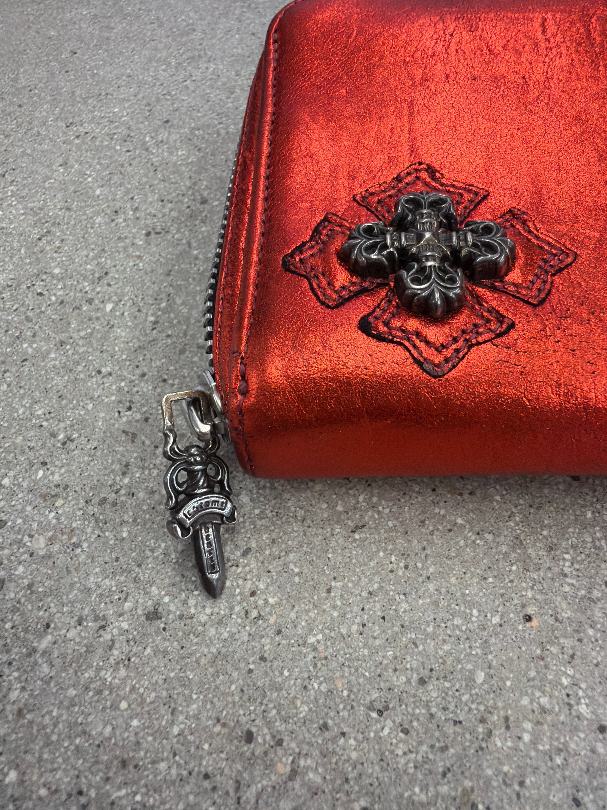 Chrome Hearts red wallet close-up of dagger zipper pull and black plus cross patch on red metallic leather
