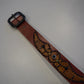 Vintage brown leather belt laid flat showing embossed spider motif, blue glass cabochons and black studs