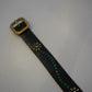 Vintage studded leather belt close-up, black hide with blue floral motif and antiqued silver buckle hardware.