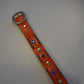 Vintage orange studded leather belt flat view, full row of metal pyramid studs across strap
