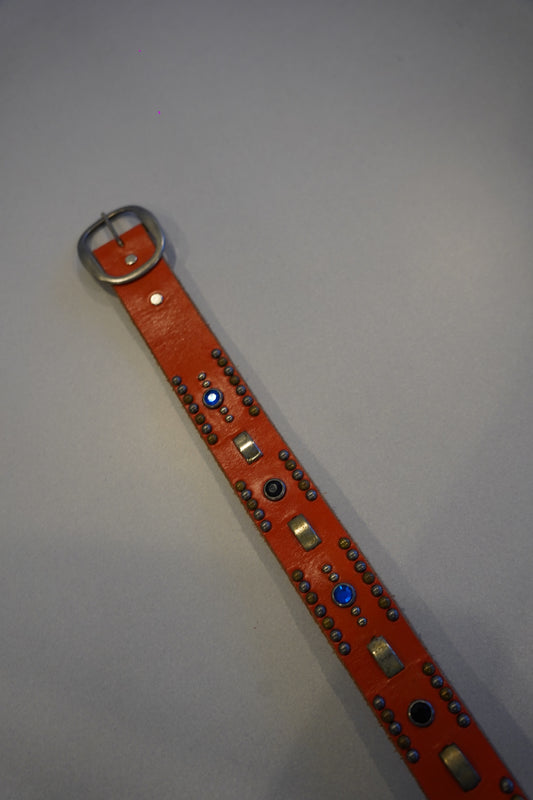 Vintage orange studded leather belt flat view, full row of metal pyramid studs across strap
