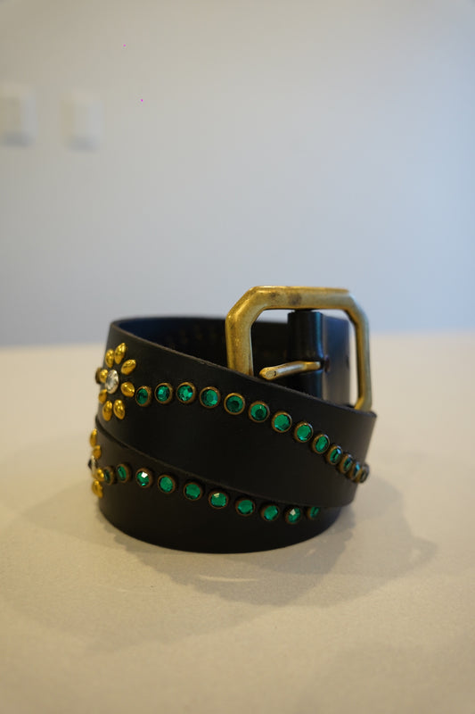 Vintage black leather studded belt coiled view, green rhinestones, gold floral conchos and brass square buckle.