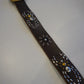 Vintage brown leather belt laid flat showing studded spider and starburst medallions along the strap