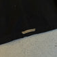 Chrome Hearts black jacket back hem detail showing engraved silver Chrome Hearts plaque tag