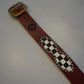 Vintage studded leather belt full length with brass buckle, black and white checkerboard inlay and silver studs.