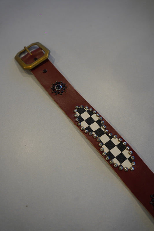 Vintage studded leather belt full length with brass buckle, black and white checkerboard inlay and silver studs.