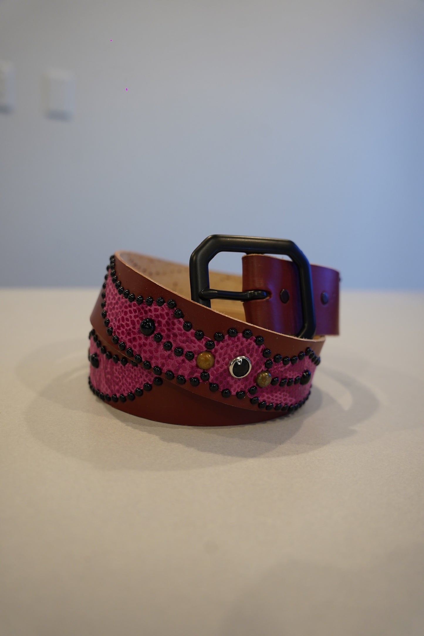Vintage brown pink snakeskin leather belt coiled with silver studded wing buckle hardware.