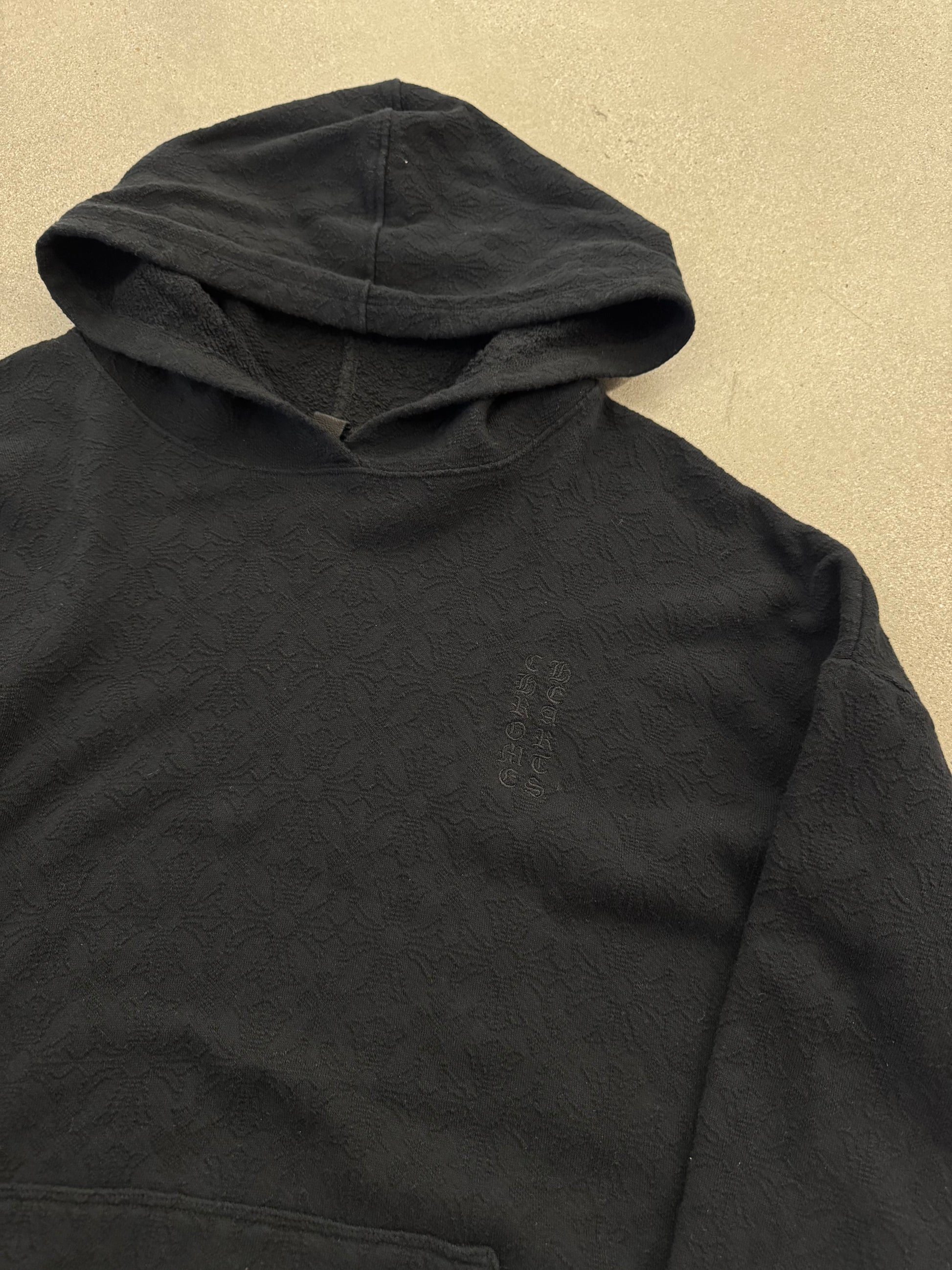 Chrome Hearts black hoodie close-up of embroidered cross logo detail at front kangaroo pocket