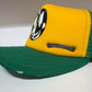 Side angle of Chrome Hearts Matty Boy yellow green trucker hat showing curved brim and silver Chrome Hearts plaque