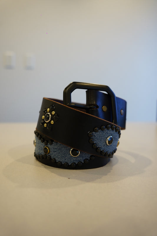 Vintage black denim leather belt with silver pyramid studs running along full length and chrome buckle.