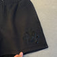 Chrome Hearts black sweat shorts close-up of layered black leather cross patches with tonal stitch detailing