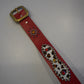 Vintage red cowhide studded belt coiled view, dense pyramid studs along strap with classic single-prong buckle.