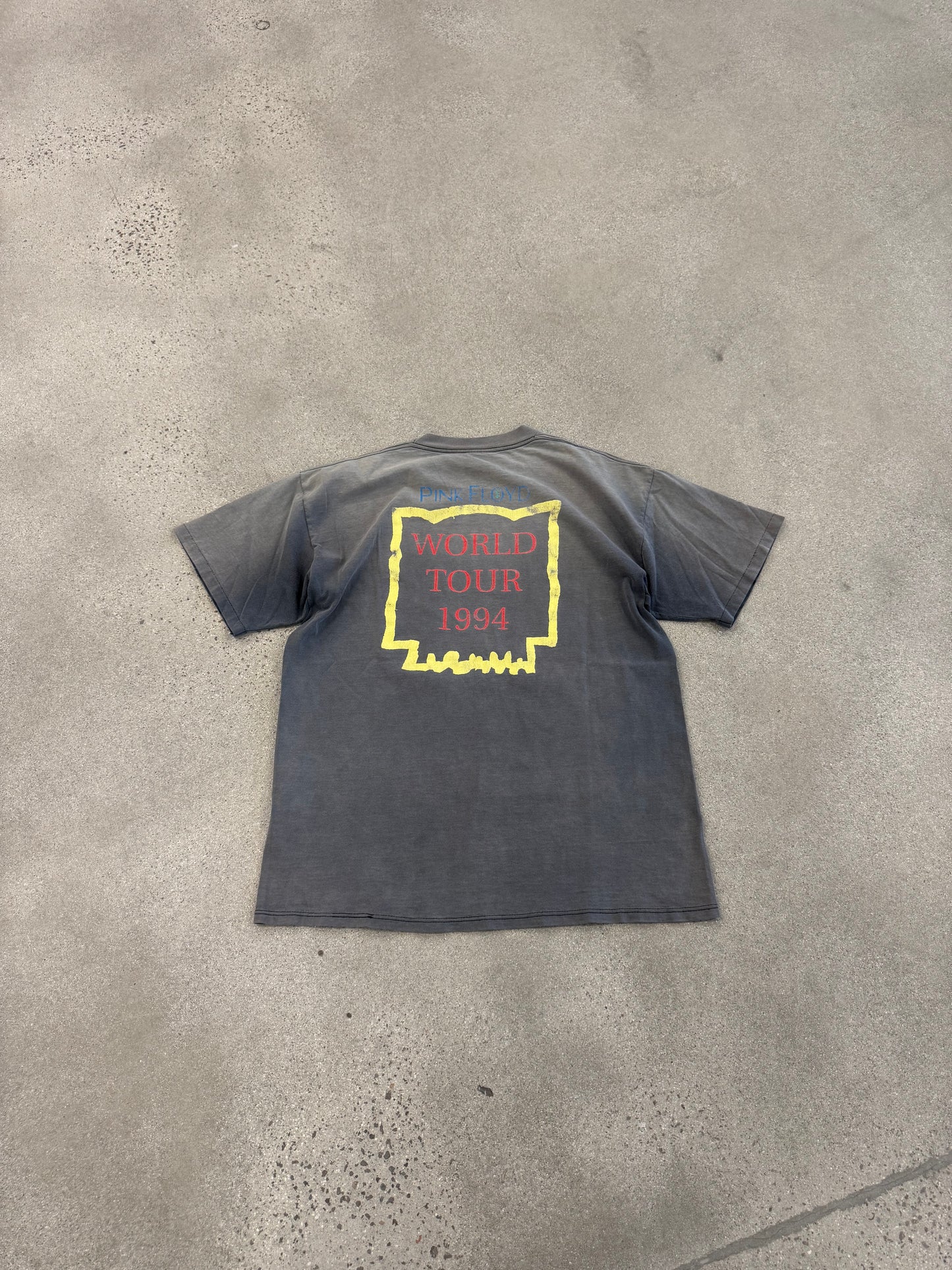 Back of vintage Pink Floyd tee on concrete showing World Tour 1994 print and overall faded vintage wash