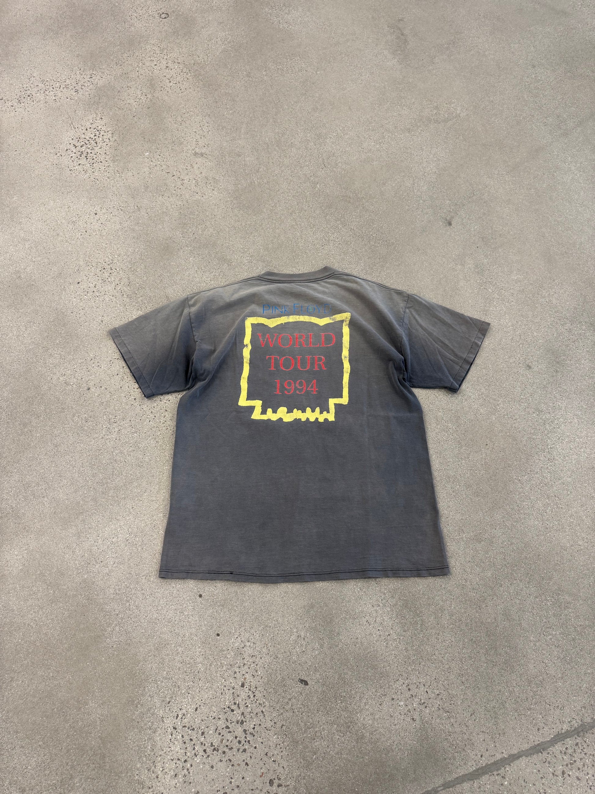 Back of vintage Pink Floyd tee on concrete showing World Tour 1994 print and overall faded vintage wash