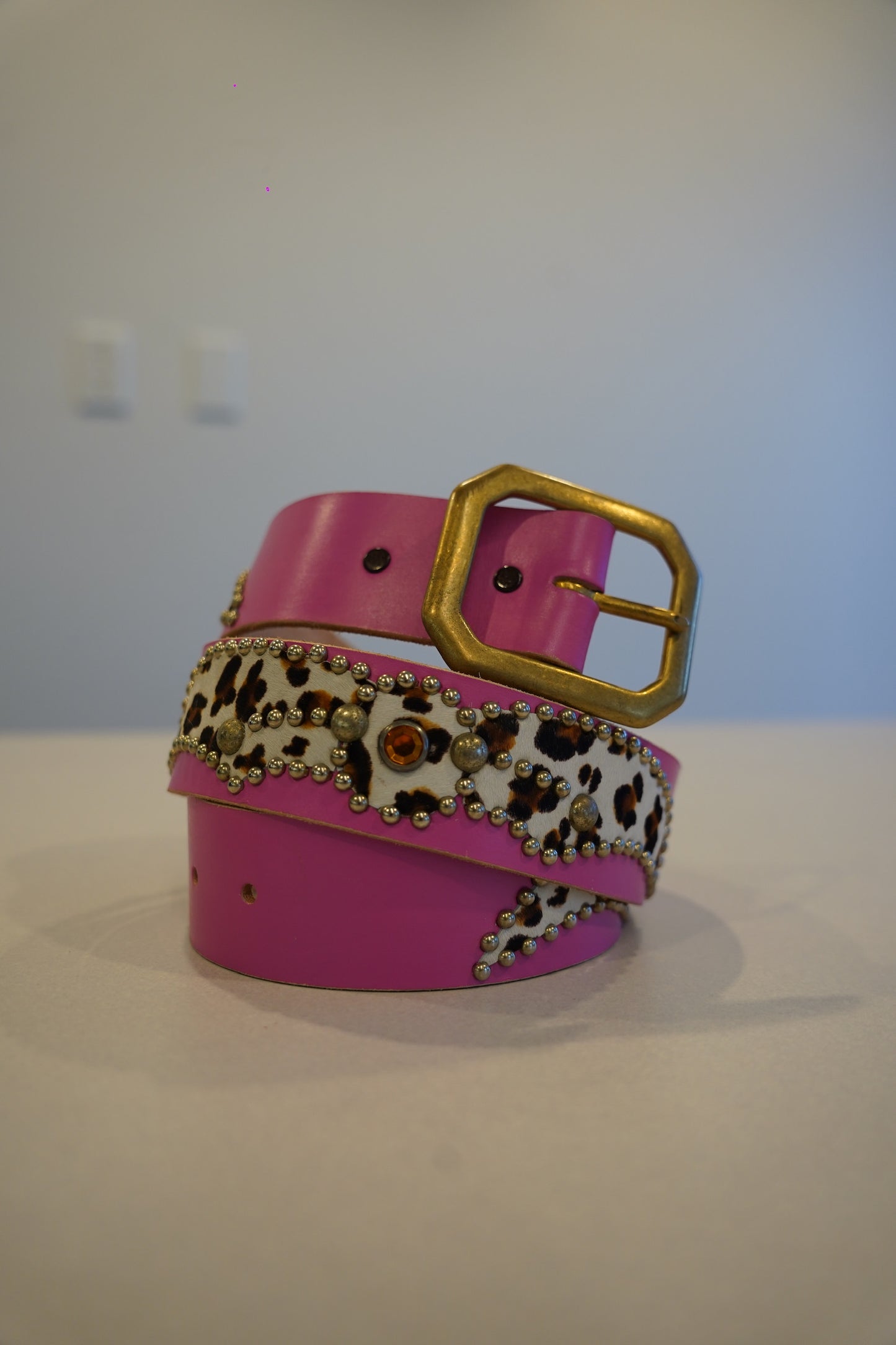 Vintage pink studded leather belt coiled, animal print panel with silver pyramid stud detail