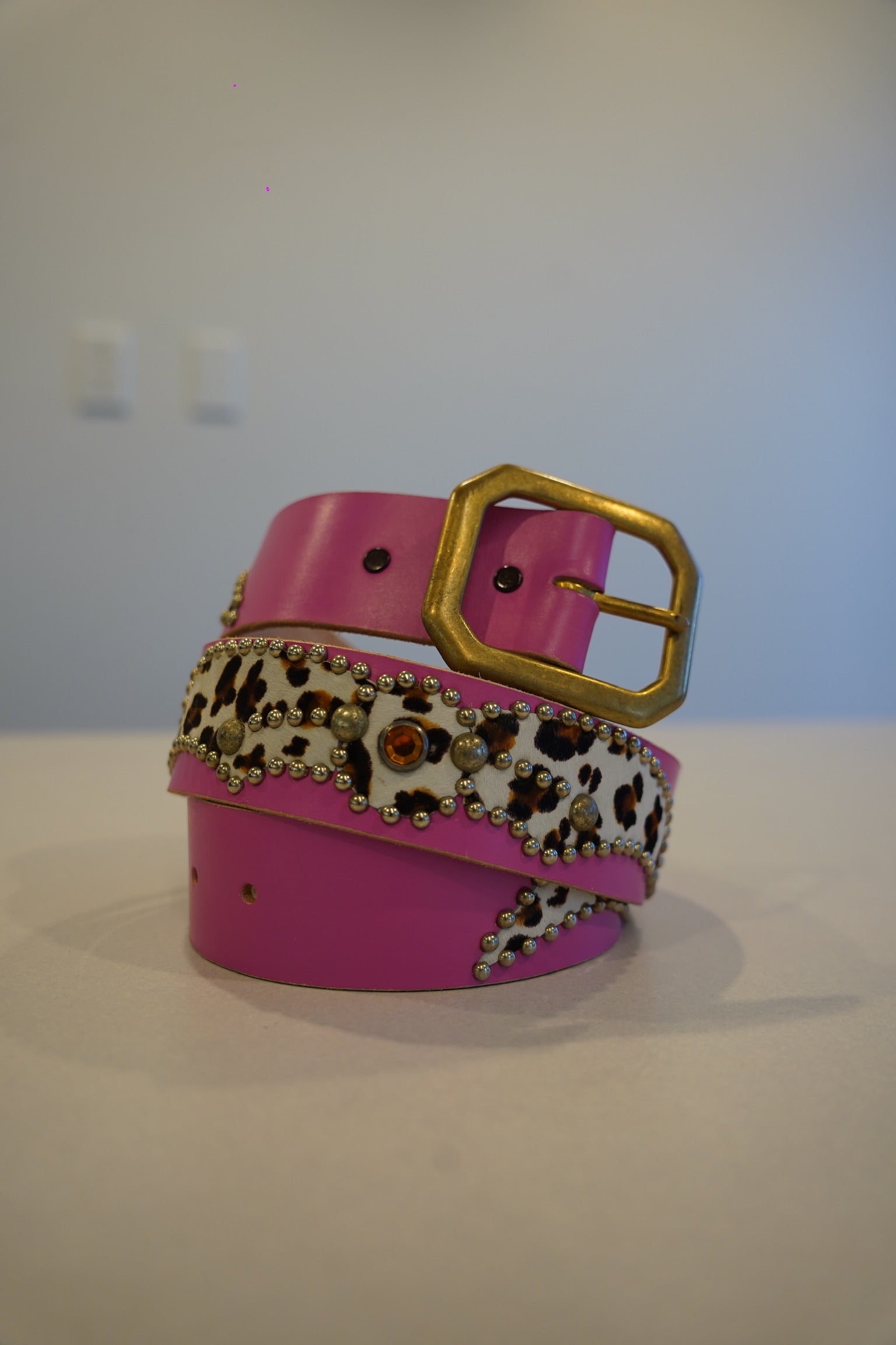 Vintage pink studded leather belt coiled, animal print panel with silver pyramid stud detail