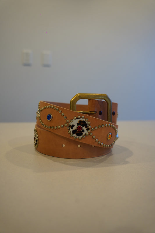 Vintage tan leather belt coiled with brass buckle, silver bead trim, leopard inlay medallions and jewel studs.