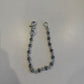 Chrome Hearts Fleur ball wallet chain draped on white surface showing silver fleur-engraved beads and hardware