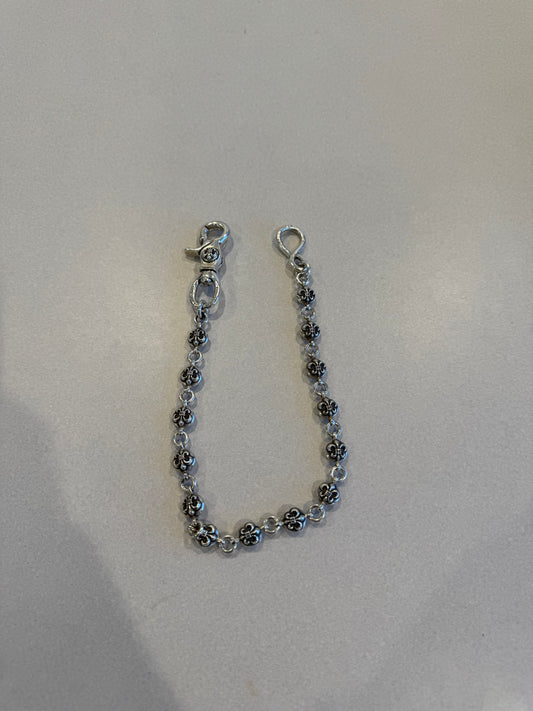 Chrome Hearts Fleur ball wallet chain draped on white surface showing silver fleur-engraved beads and hardware