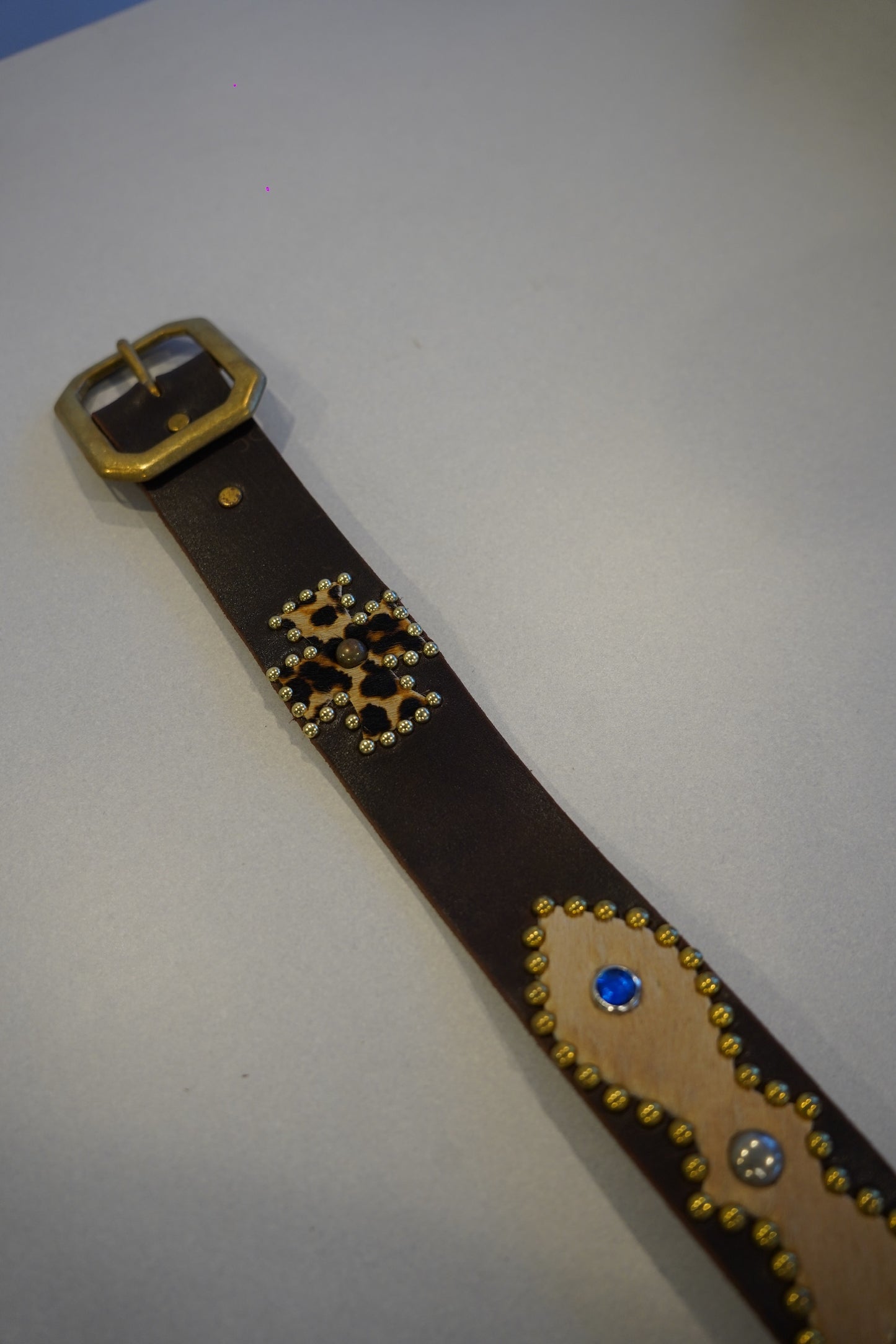 Buckle detail of vintage brown leather studded belt with brass hardware and leopard hair-on appliques