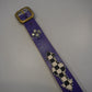 Vintage purple leather belt laid flat showing brass buckle, silver cross studs and checkered diamond panel detail.