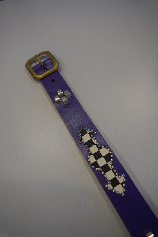 Vintage purple leather belt laid flat showing brass buckle, silver cross studs and checkered diamond panel detail.